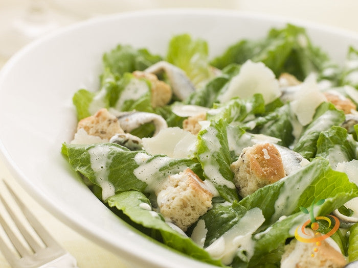 Fresh romaine lettuce salad with croutons and creamy dressing in a white bowl