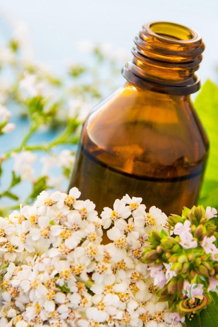 Amber glass bottle with yarrow white flowers and green foliage in the background
