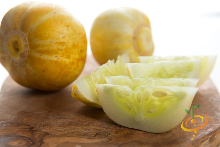 Lemon cucumber whole and sliced on wooden board showing yellow skin and pale green interior seeds
