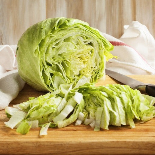 Iceberg lettuce seeds from SeedsNow, showing fresh green lettuce heads with crisp leaves on a garden table.