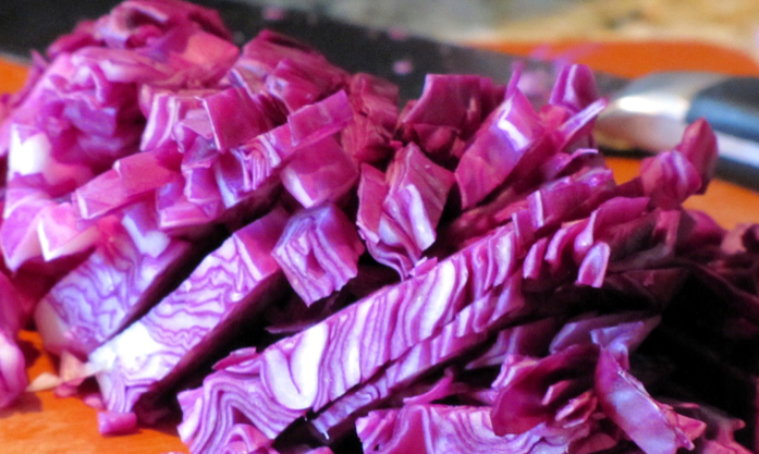 Close-up of chopped red cabbage on a cutting board, showcasing the vibrant purple and white layers of Red Acre seeds variety.